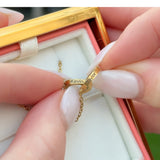 Close-up of hands holding the gold double-heart necklace, engraved with two names.